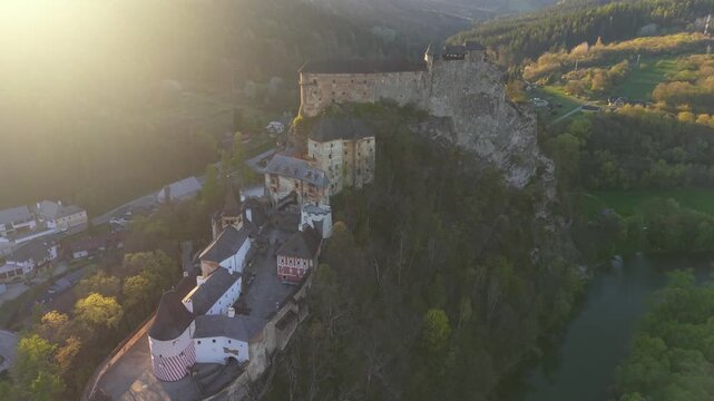 Stunning aerial footage showing the historic Orava Castle perched on a cliff above the Orava River in Slovakia during a beautiful sunset