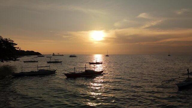 Drone ascends over boats on the ocean at sunset in Panglao, Bohol