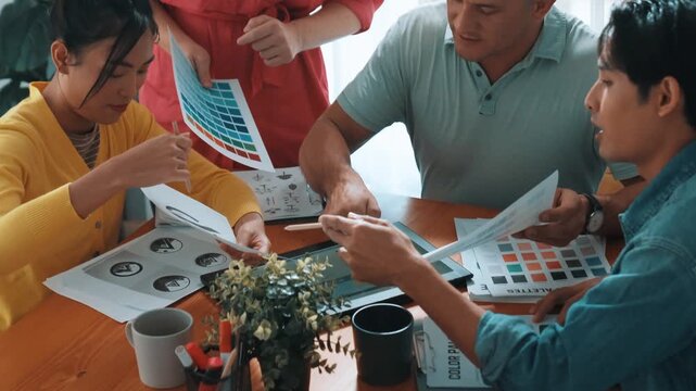 Top view of business people working together to choosing color from color palette. Project manager present idea by using tablet to marketing team while business man looking at logo graphic. Symposium.