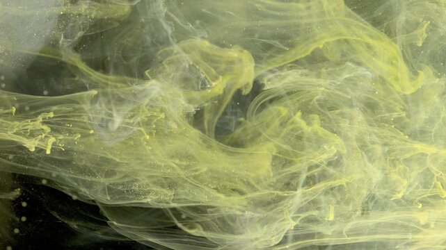 Yellow smoke swirling in water, amorphous cloud drifting across black backdrop with fine particles and wispy tendrils, cinematic fluid textures
