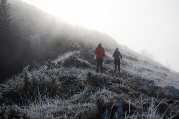 Fototapeta premium Couple Hiking on Frosty Mountain Trail in Foggy Morning Light