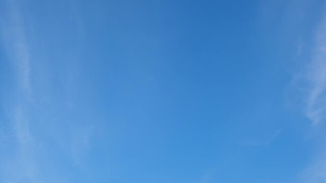 A blue sky timelapse video footage featuring thin cirrus clouds surrounding a clear atmosphere, capturing bright daylight, smooth cloud flow, open sky scenery, and calm natural weather patterns. 4k.
