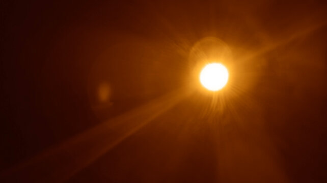 abstract image of light burst among trees and glitter bokeh. image is blurred. yellow golden bokeh pattern background. Real optical lens flare on black backdrop. sunrays, sun rays beam, burst, sunbeam