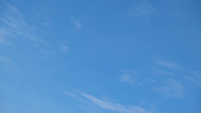 A blue sky timelapse video footage featuring wispy cirrus clouds drifting across a vibrant atmosphere, capturing gentle wind patterns, bright daylight, peaceful weather, and open sky tranquility. 4k.

