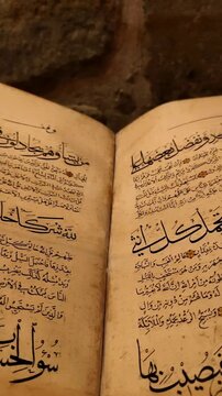 Horizontal pan showing the transition between two pages of an open ancient Quran manuscript