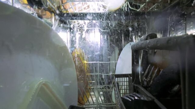 Interior View of Running Dishwasher with Water Jets and Clean Plates