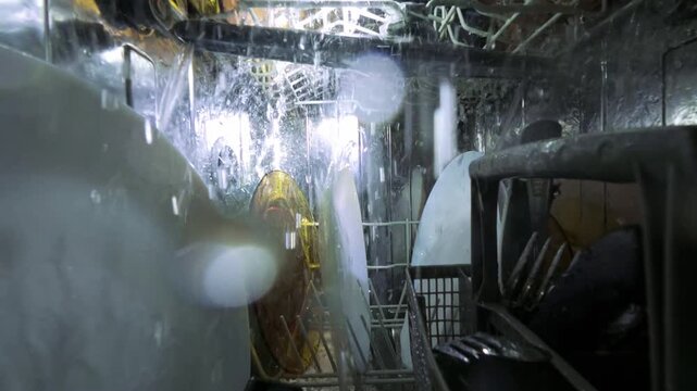 Interior View of Running Dishwasher with Water Jets and Clean Plates