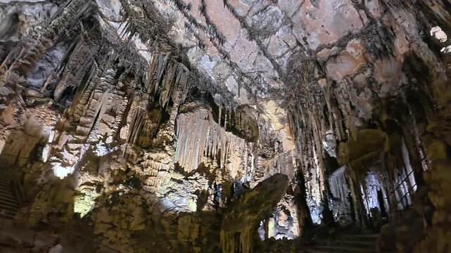 Detailed view of massive stalactites and stalagmites in a limestone cave in Mallorca. Underground geological formations in 4K 30fps for tourism.