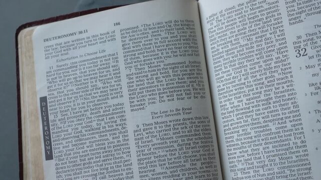 Holy Bible open up to the book of Deuteronomy of the old testament, zooming into Chapter 31 verse 6 on being strong and courageous. New Revised Standard Version.