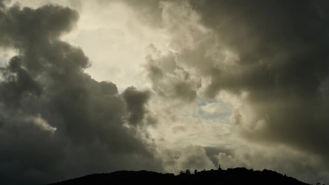 Dramatic storm clouds moving over a silhouetted hilltop temple