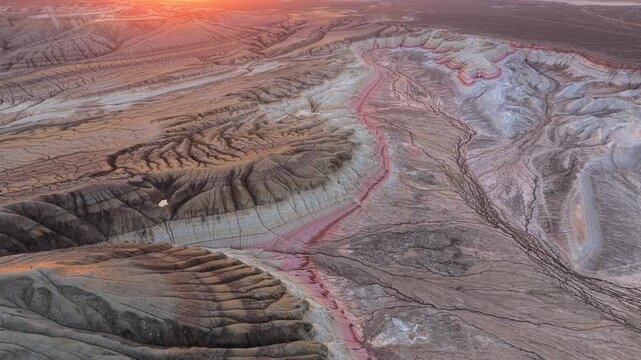 Aerial view of the colorful mineral layers and eroded terrain of Gora Bokty during sunset in Karakiya District, Mangystau Region, Kazakhstan.