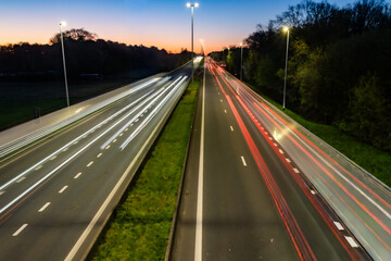 Obraz premium Highway Traffic Light Trails at Twilight - Long Exposure of Cars in Motion on Multi-Lane Road