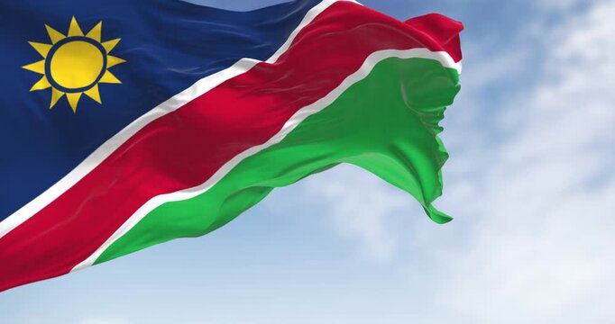 Namibia national flag waving on a clear day. Blue stripes, yellow sun, red, white stripes, green. Ovambo color. Seamless 3d render animation. Slow motion loop. Selective focus