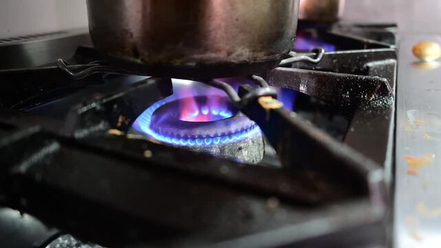 Saucepan sitting on a lit gas stove burner