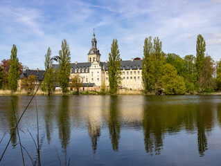 Obraz premium Historic Park Abbey near Leuven Belgium reflected in tranquil lake with spring trees