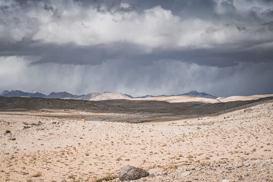 Mountain landscape, rocky peaks and ridges with snow and glaciers, a panorama in the mountains. Tien Shan in the Pamirs, desert terrain and cloudy weather with rain in the high mountains