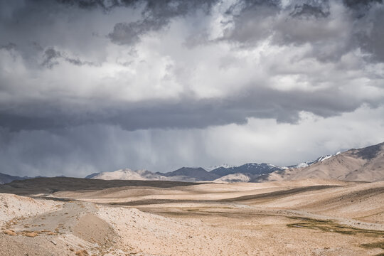 Mountain landscape, rocky peaks and ridges with snow and glaciers, a panorama in the mountains. Tien Shan in the Pamirs, desert terrain and cloudy weather with rain in the high mountains