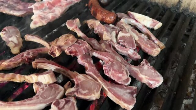 Lamb chops and steaks sizzling on a charcoal barbecue grill