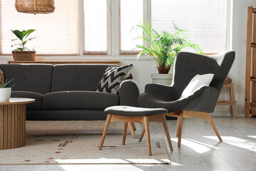 Interior of stylish living room with cozy grey armchair, sofa and wooden coffee table