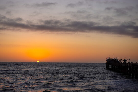 As the sun sinks beyond the Atlantic, the waterfront of Swakopmund&nbsp;glows in warm light, where ocean mist, silhouettes, and evening colors merge into a calm coastal scene.