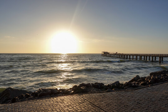 As the sun sinks beyond the Atlantic, the waterfront of Swakopmund&nbsp;glows in warm light, where ocean mist, silhouettes, and evening colors merge into a calm coastal scene.