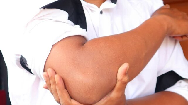 Asian man touching the elbow with elbow pain And he relieves pain with massage. Health and healing concept.
