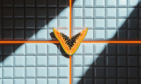 Papaya slice tiles symmetrical orange and blue fruit arrangement on a geometric grid with copy space for design projects