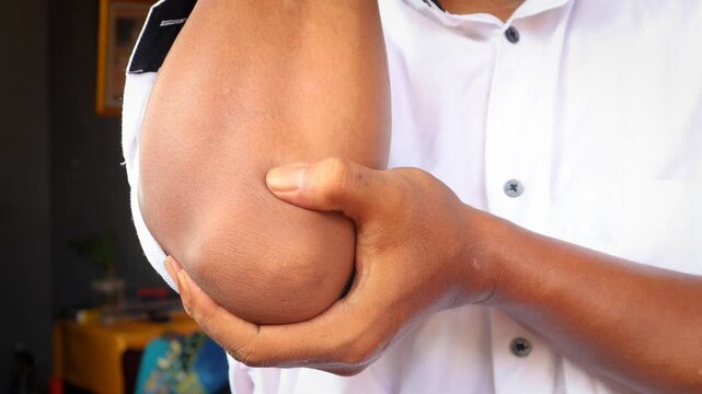 Asian man touching the elbow with elbow pain And he relieves pain with massage. Health and healing concept.