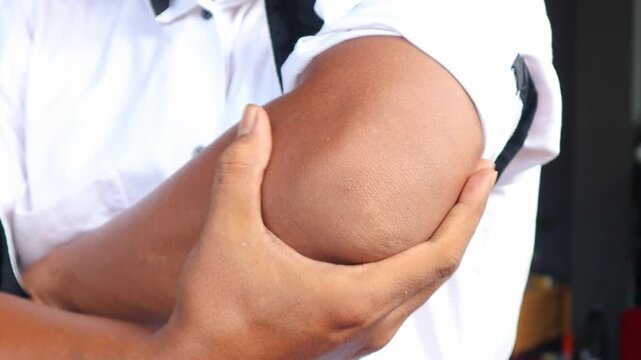 Asian man touching the elbow with elbow pain And he relieves pain with massage. Health and healing concept.