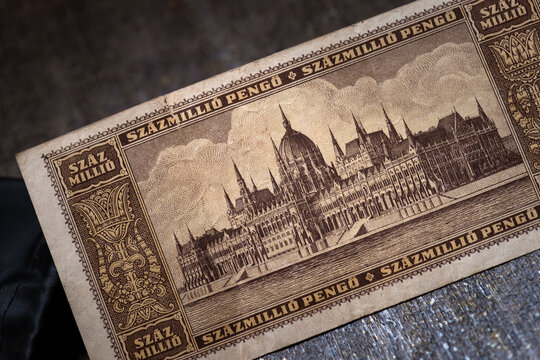 Closeup photo of the reverse side of a vintage Hungarian Szazmillio Pengo banknote, featuring detailed architectural illustration, ornate border design, and aged paper texture.