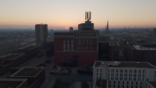 Ascending aerial footage of the dortmund u tower, a famous german landmark, against a sunset sky
