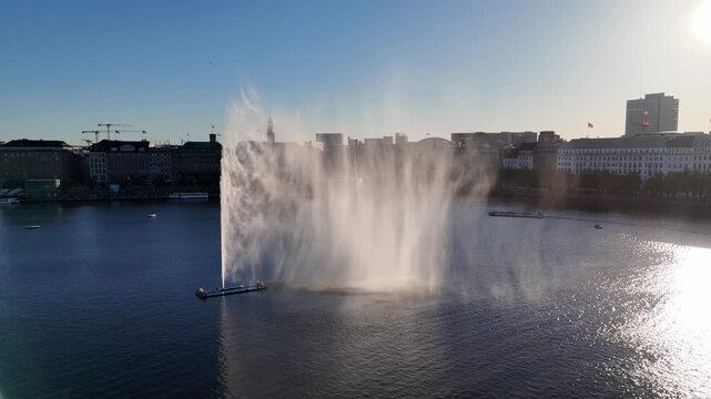 Aerial view of the Alsterfontane fountain spraying water high into the air on the Binnenalster lake with the city skyline in the background in Hamburg, Hamburg, Germany.