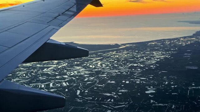 An airplane wing glides over a reflective landscape during sunset, capturing the serene transition of colors. Ideal for travel or aviation themes.