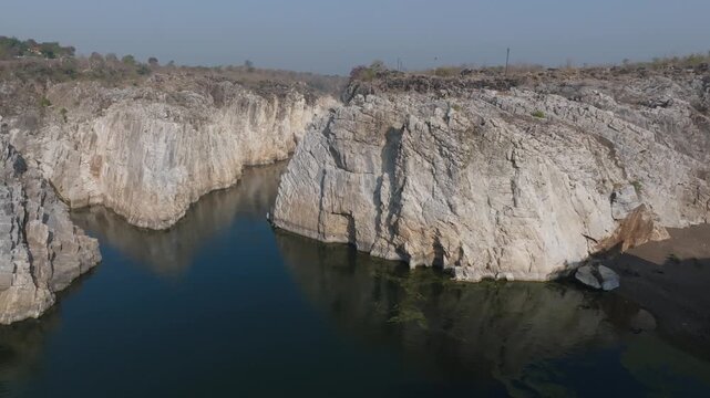 Bhedaghat's Marble rock formation near Swarg Dwari tower above the Narmada River in Jabalpur district, Madhya Pradesh. Aerial reveal of the Limestone canyon walls and calm valley gorge below.