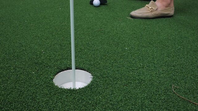 Close-up of a golf ball and putter on artificial turf