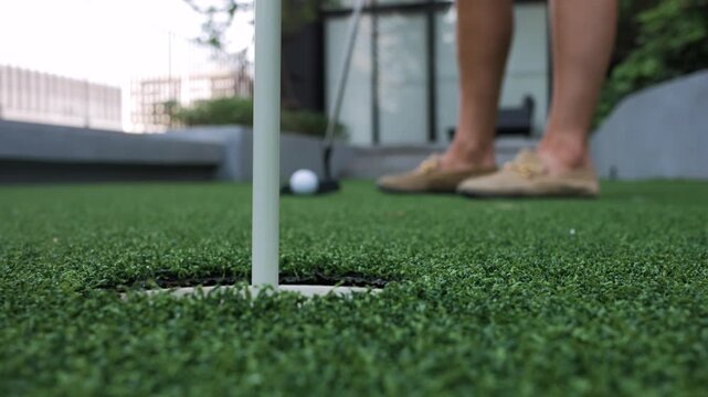 Close-up of a golf ball and putter on artificial turf