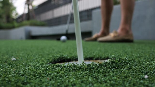Close-up of a golf ball and putter on artificial turf