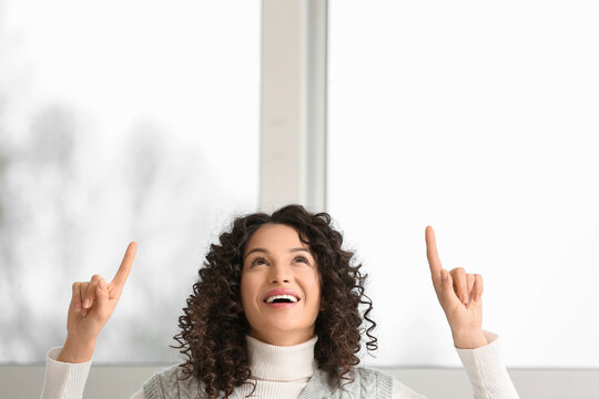 Young businesswoman pointing at something near window in office