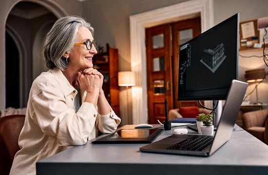 enior woman designing 3d model on laptop and monitor at home.