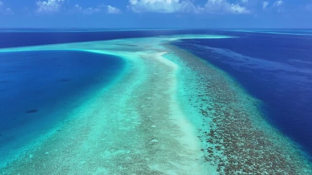 Aerial view of a long coral reef and turquoise lagoon stretching into the deep blue ocean under a clear sky Kendhoo, Baa Atoll, Maldives.