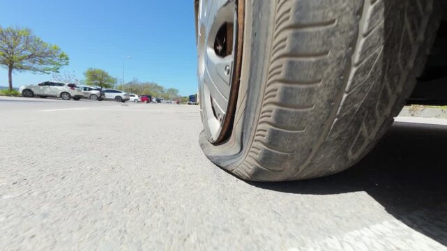 Car driving on a completely flat tire on the asphalt road