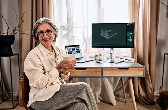 Senior woman working at home office with computer and coffee.