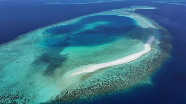 Aerial view of a pristine white sandbar surrounded by turquoise lagoon waters and vibrant coral reefs in Kendhoo, Baa Atoll, Maldives.