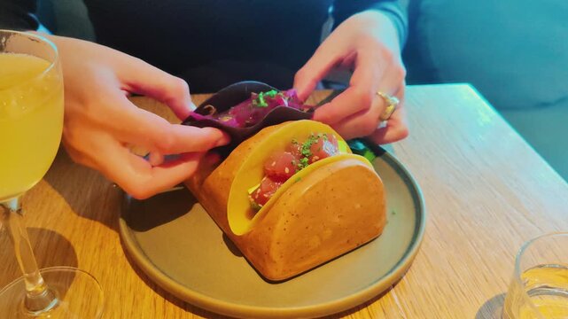 Hands Presenting Gourmet Tacos On Wooden Stand In Restaurant. Close-up of restaurant dining and food presentation featuring fresh fillings, vibrant tortillas, and careful plating.