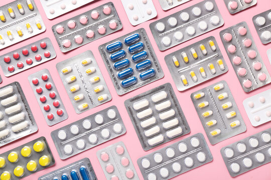 Blister packs with different pills on pink background