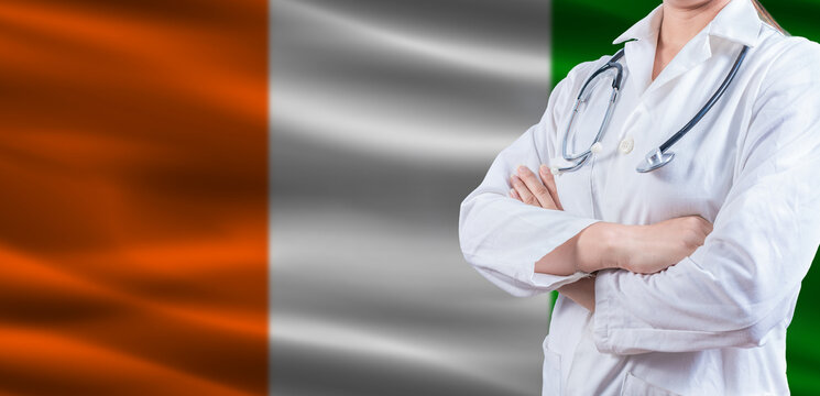 Doctor with crossed arms on Ivory Coast flag. Ivorian health and care concept. Female doctor on Ivory Coast flag