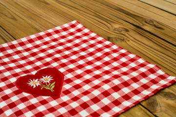 Obraz premium Red and white checkered tablecloth with heart design on wooden table during daylight