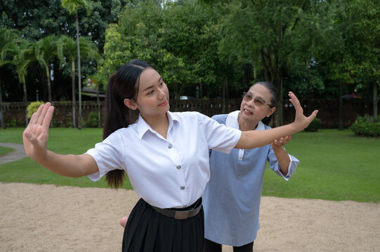 Asian dance instructor teaching young Thai student dancing Thai classic dancing in outdoor park