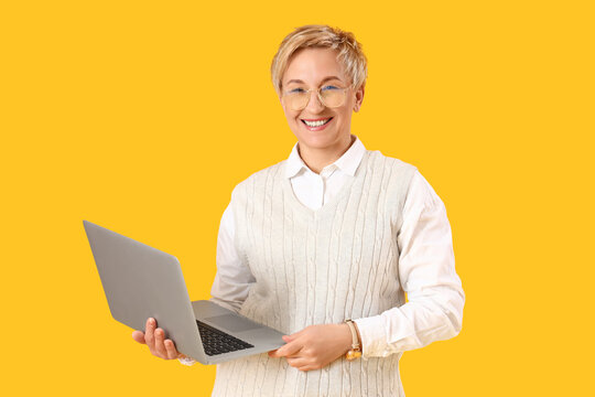 Mature female programmer with laptop on yellow background
