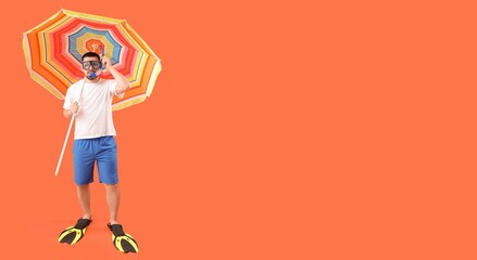 Young man with diving flippers, snorkeling mask, tube and beach umbrella on orange background with space for text © Pixel-Shot